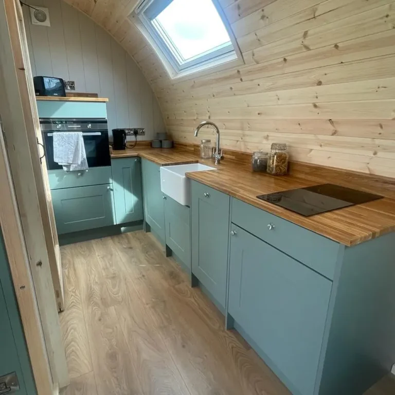 Fully Equipped Kitchen Includes a modern gully kitchen with a solid worktop, two-ring hob, combination oven, fridge with freezer compartment, and undermount sink.